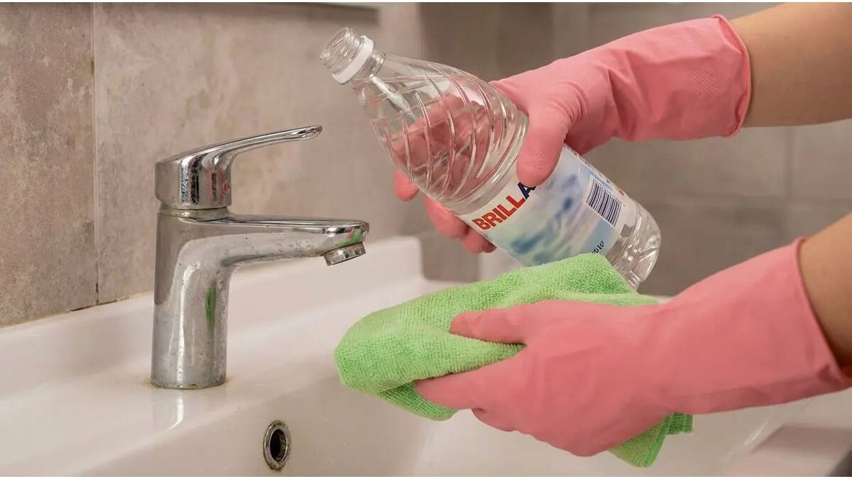 Bottiglia di aceto e panno vicino a una porta del bagno.